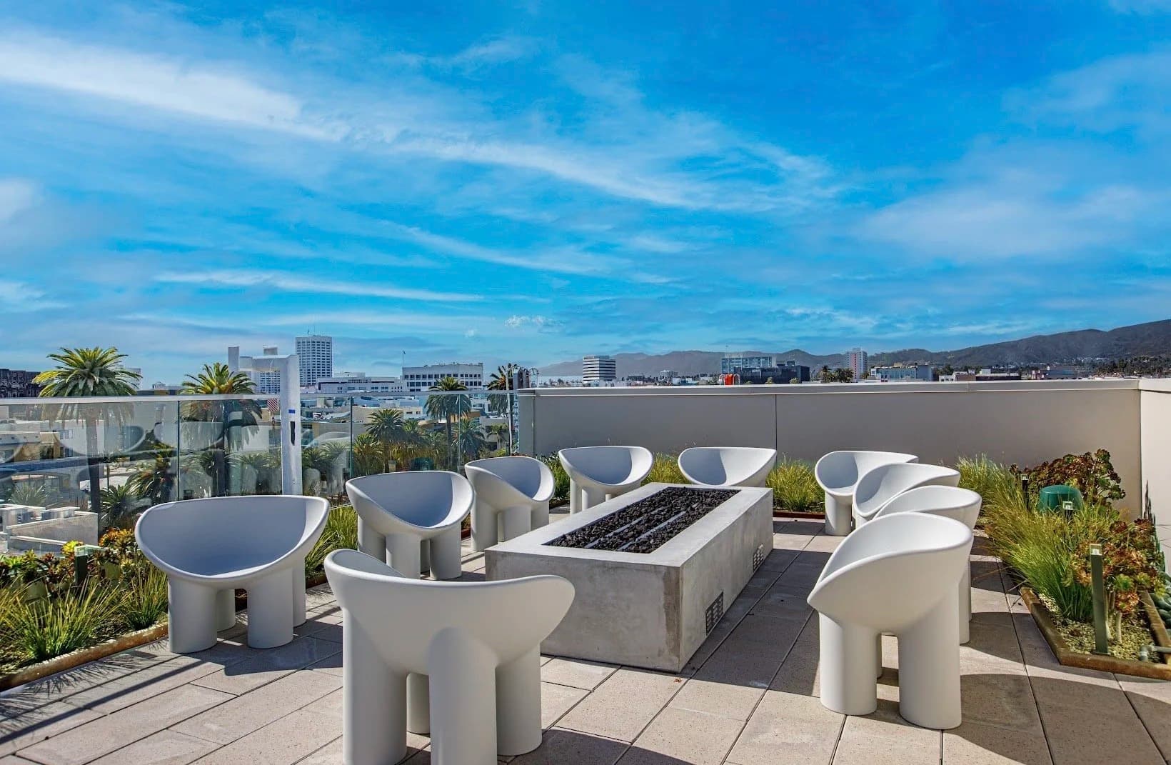 Rooftop lounge with fire pit and designer chairs framing Santa Monica city and mountain views